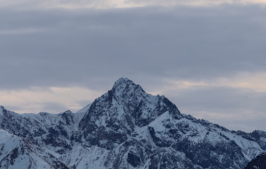 Beautiful winter mountain landscape at the sunrise with dramatics clouds. High snow covered mountains in the fog.