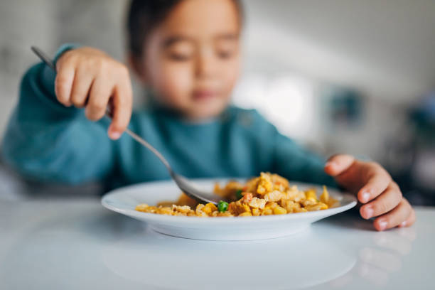istock Close-up of a plate with fried rice from which a three-year-old boy eats with a spoon while sitting at a table. 1370341389