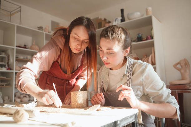 istock Professional potter teaching pottery to a woman 1370341406