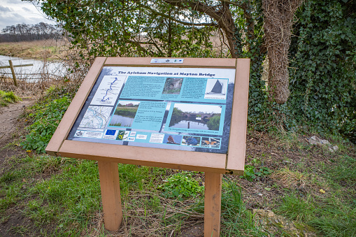 Coltishall, Norfolk, UK - February 2022. Tourist and visitor information board of the history of The Aylsham Navigation at Mayton Bridge on the bank of the River Bure, Norfolk Broads