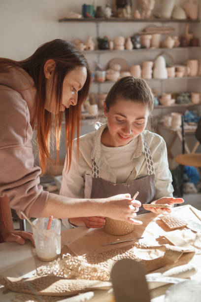 istock Professional potter teaching pottery to a woman 1370341594