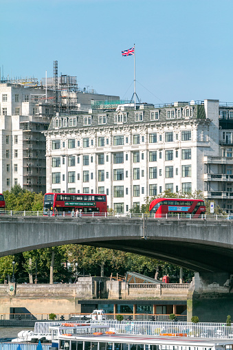 Double-Decker Buses on Waterloo Bridge near Savoy Hotel in City of Westminster, London. Commercial signs can be seen on the buses.