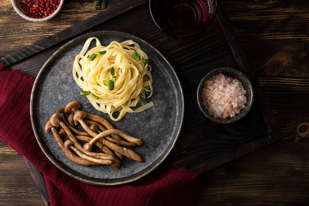 Plate with fried mushrooms and pasta, cooked shimeji and noodles. Plate with fried mushrooms and pasta, cooked shimeji and noodles on wooden background. buna shimeji stock pictures, royalty-free photos & images