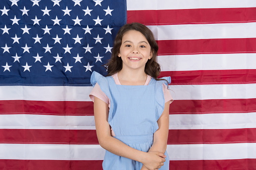 Free born and free bred. Carefree small child enjoying happy childhood. Happy little girl smiling on american flag decor. Free development. Free expression of the will.
