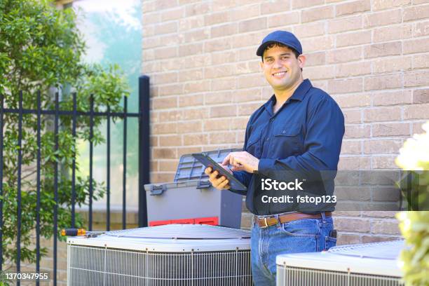 Latin Descent Young Man Blue Collar Air Conditioner Repairman At Work Stock Photo - Download Image Now