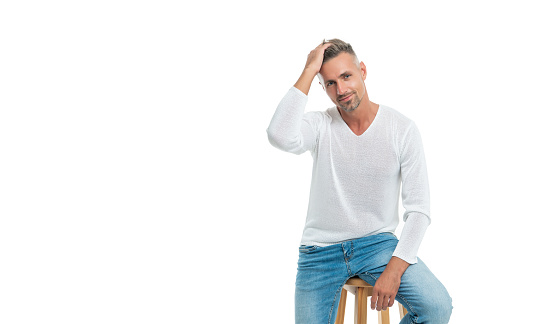 male fashion model in casual style clothes sit on chair isolated on white background with copy space, fashion.