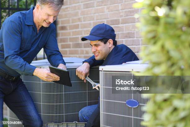 Multiethnic Team Of Blue Collar Air Conditioner Repairmen At Work Stock Photo - Download Image Now