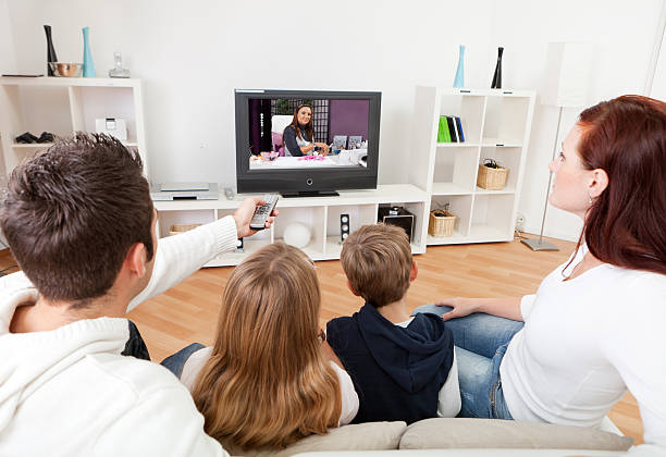 jeune famille regarder la télévision à la maison - mother holding child pointing photos et images de collection