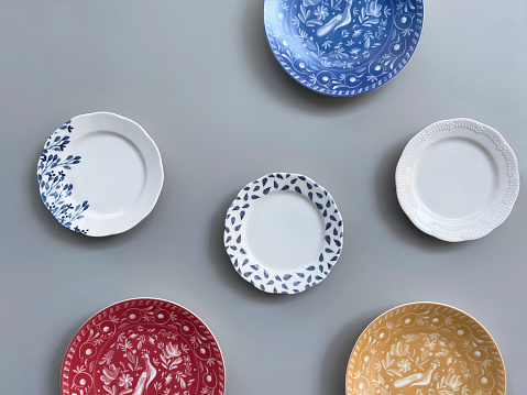 Group of ornate plates hanging on the gray wall background with copy space, plates variation