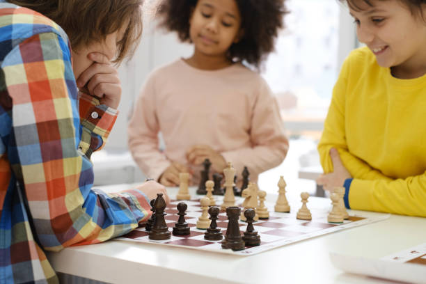 enfants multiethniques jouant à un jeu d’échecs à l’école - chess skill concentration intelligence photos et images de collection