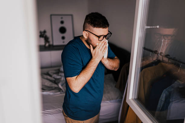 istock Shot of a young man suffering with flu while sitting on bed 1370354504