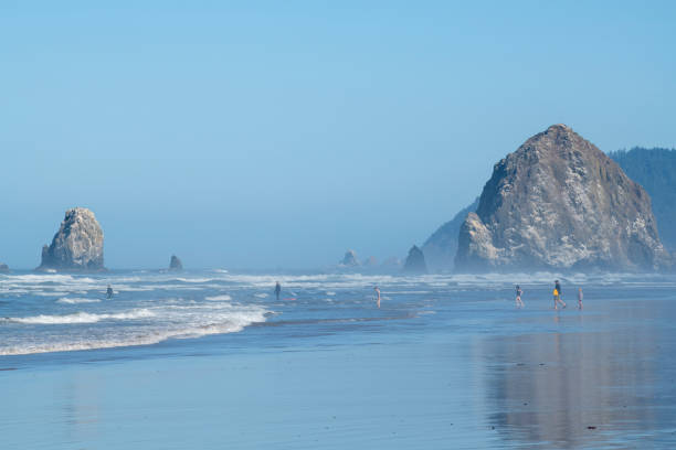 Cannon Beach, USA - September 6, 2021. Adults and children walking toward waves on Cannon Beach, Oregon, USA