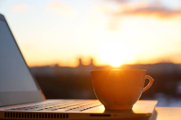 xícara de café e laptop na mesa contra a janela com sol - heat snow urban scene creativity - fotografias e filmes do acervo