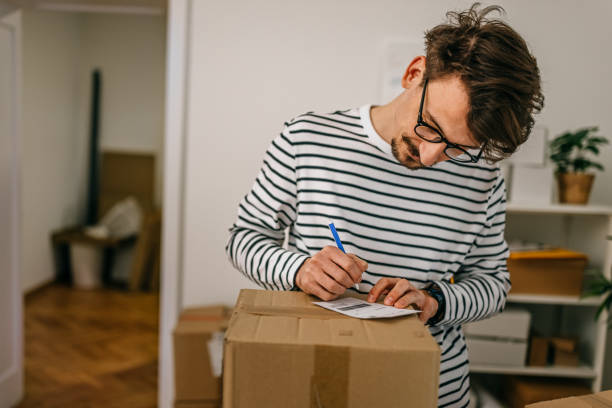 istock Businessman writing on cardboard box label in office 1370355123