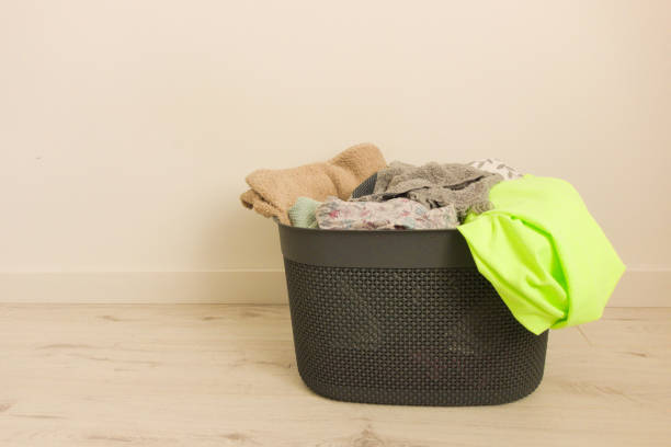 Individual holding a laundry basket with bird patterns. Person in casual attire doing household chores. Domestic life and home organization concept.