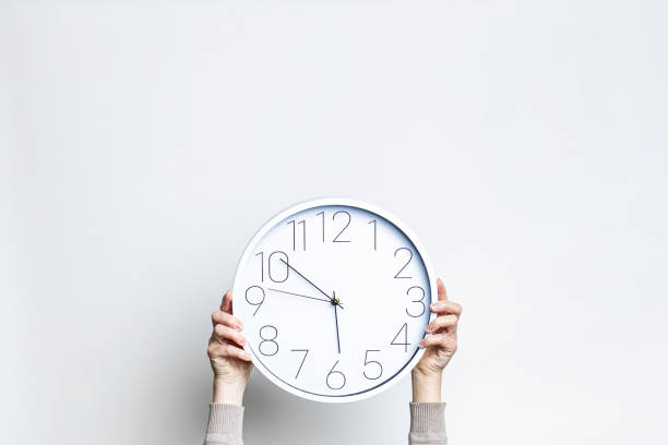 istock Female hands holding a large white watch on a light background. 1370357255