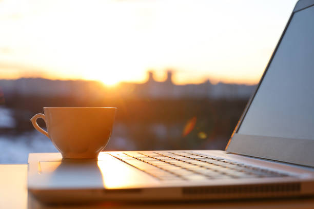 Coffee cup on laptop against the window with sunshine