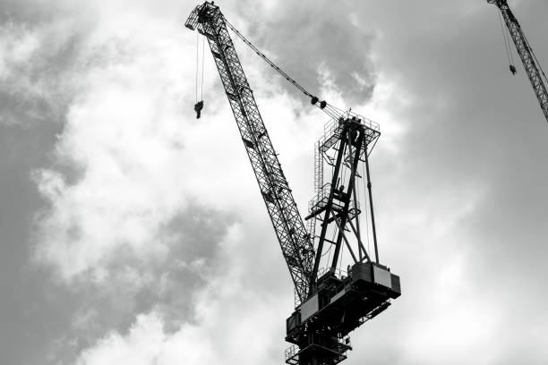 istock Black and white Tower crane at construction site against dark sky background with copy space 1370360220