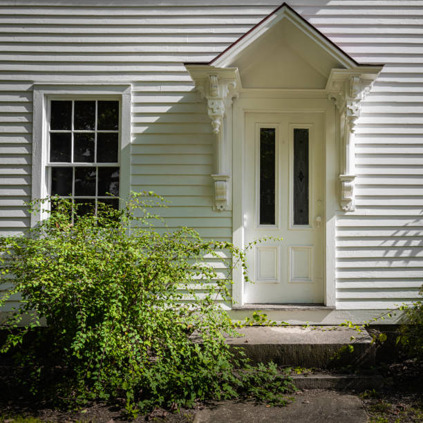 メインエントランスドアと白いサイディングと緑の茂みを持つ家の窓 - colonial style house residential structure siding ストックフォトと画像