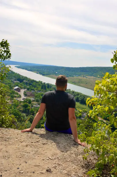 Photo of a man sits on the edge of a cliff and loves the scenery