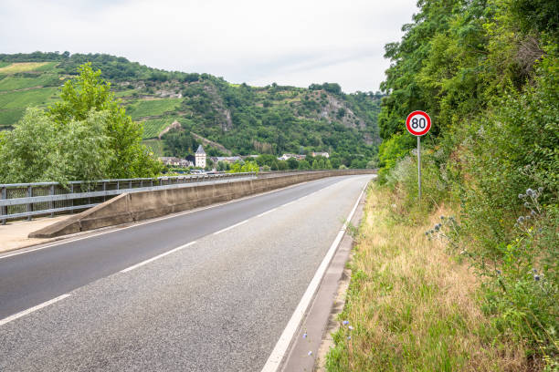 Deserted road running along a river at the bottom of a valley on a cloudy summer day. River Rhine valley, Germany.