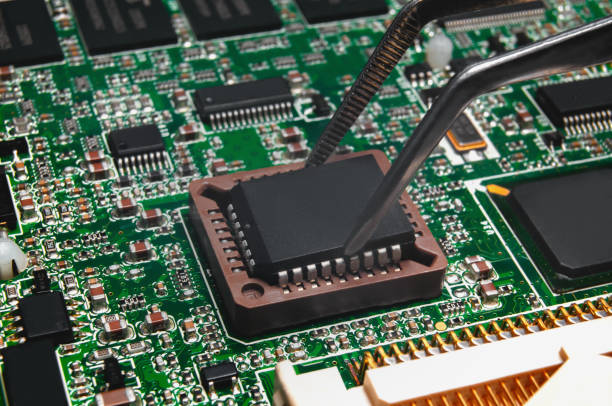 istock Integrated circuit is installing by tweezers to PLCC socket on Printed Circuit Board with integrated circuits and many other passive electrical components. Upgrade, fix and repair concept. 1370366898