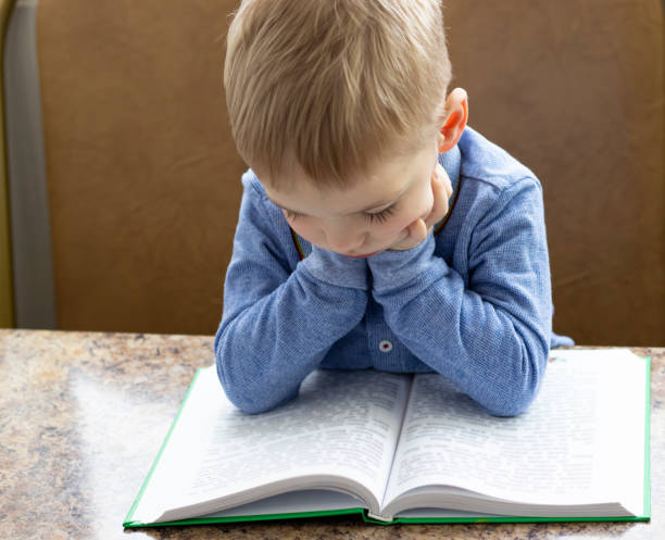 istock close-up of a pensive blond-haired toddler leaning over a book 1370367384