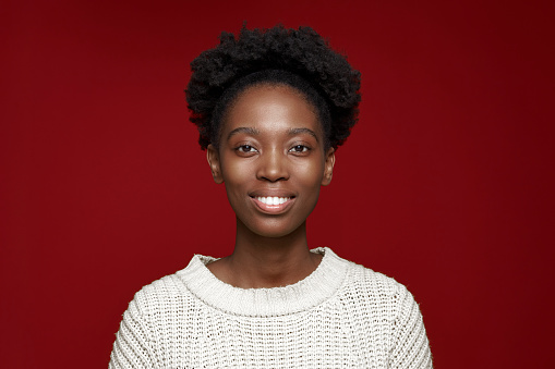 Headshot portrait of toothy smiling african american woman on red background, happy ethnic black girl with white teeth look at camera satisfied with dental treatment. High quality photo