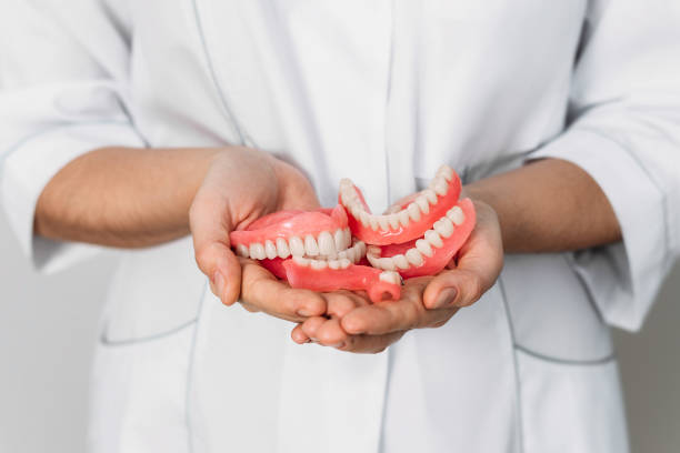 An orthopedic dentist holds dentures in his hands. Dentures in the hands of a doctor. Orthopedic dentistry. False teeth. Dentistry conceptual photo. A large number of dentures in the hands of a doctor stock photo