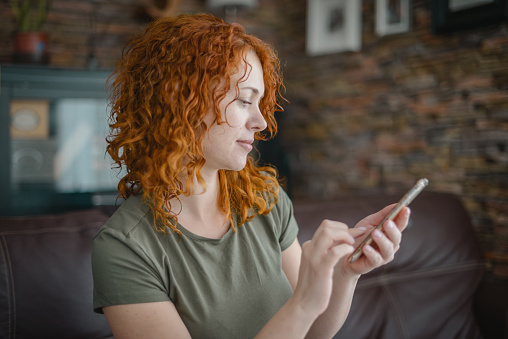 woman sitting on sofa in room with mobile phone