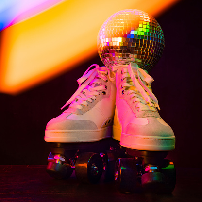 White roller skates illuminated with bright light on the dance floor.
