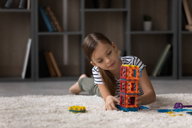 istock Little girl playing with colorful plastic blocks alone, building tower 1370375771
