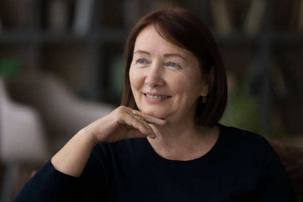istock Head shot smiling dreamy mature woman visualizing good future 1370375908