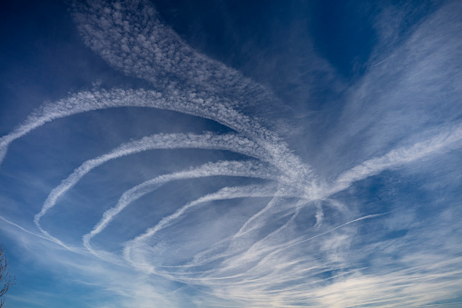 Distant passenger jet plane flying on high altitude on clear blue sky leaving white smoke trace of contrail behind. Air transportation concept