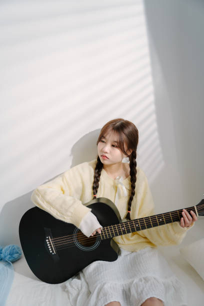 Asian young women playing guitar in bed