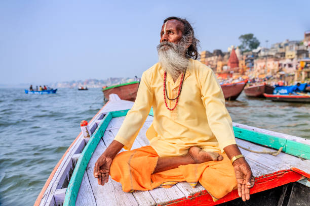 садху является meditating в лодке на священный река ганг, варанаси - varanasi indian culture nautical vessel ganges river стоковые фото и изображения
