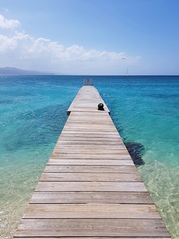 Wooden pier towards the horizon of crystal clear water.