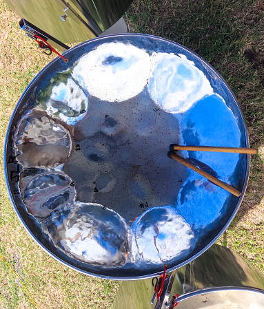 An overhead view of a steel pan drum with drum sticks lying in the drum