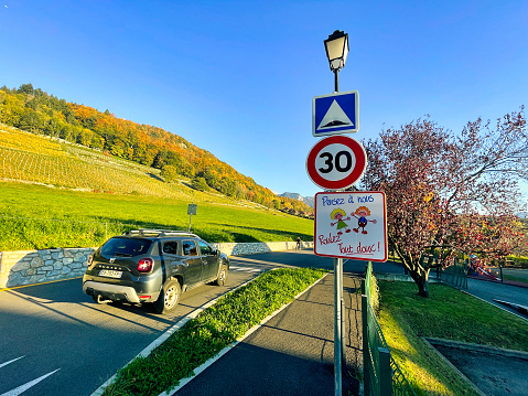 Menthon saint Bernard, France - October 23 2021: a car is passing a road sign near a french school indicating a speed limitation, a bump, and indicates that children are playing here