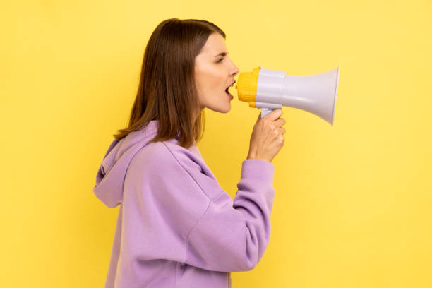 Woman screaming in megaphone and announcing discounts in mall. stock photo