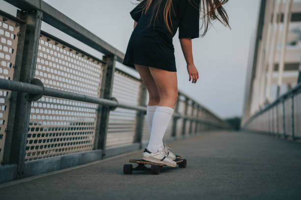 istock Young woman riding her longboard on the bridge 1370391448