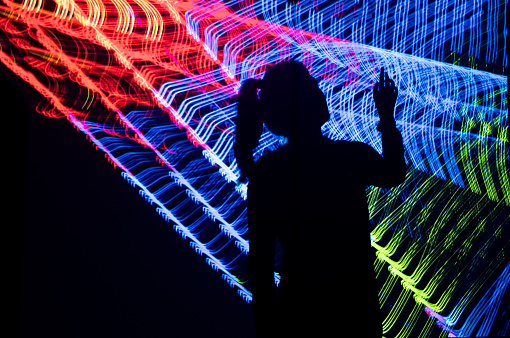 Young Woman Pointing to Light Pattern in the Dark