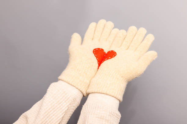 Manos de mujer con guantes blancos de punto con corazón rojo - foto de stock