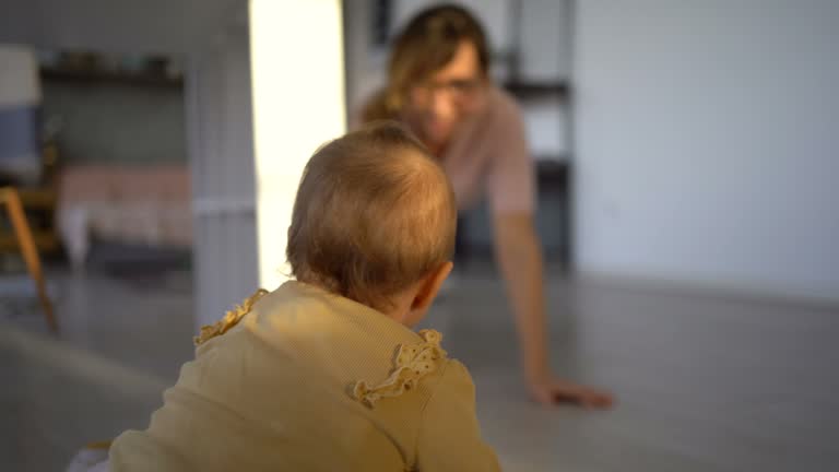 Mother and baby playing chasing game at home