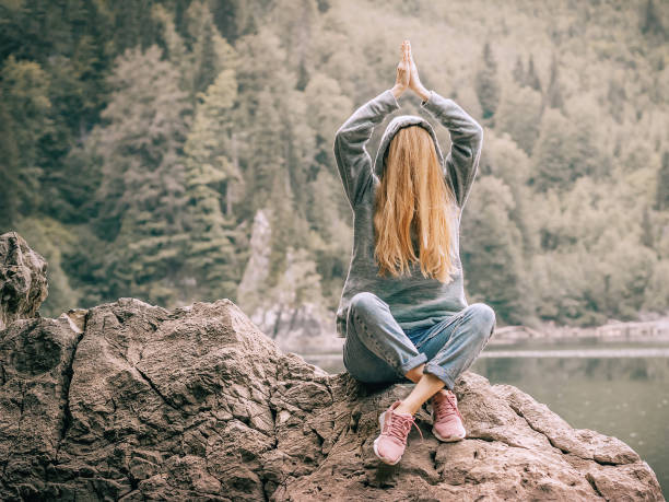 istock A woman sits on a large rock with her hands folded over her head and her face hidden under her hair near a lake in the forest. Joking photo 1370398061