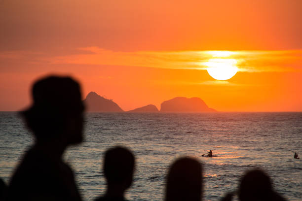 silhouette of people watching the sunset at arpoador beach in rio de janeiro, brazil.