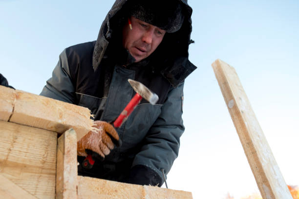 istock Worker in winter overalls with a hammer in his hand 1370404079