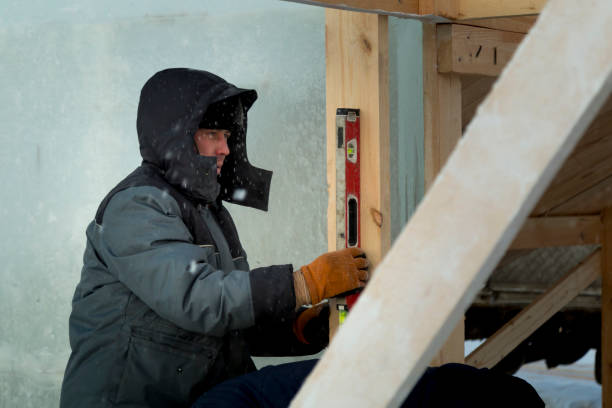 istock Worker in winter overalls with a hammer in his hand 1370404112