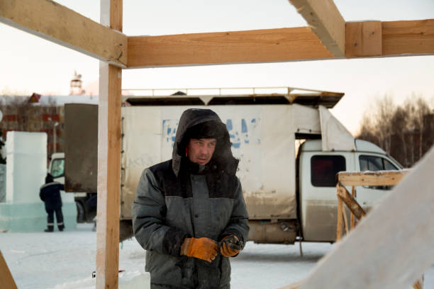 istock Worker in winter overalls with a hammer in his hand 1370404116