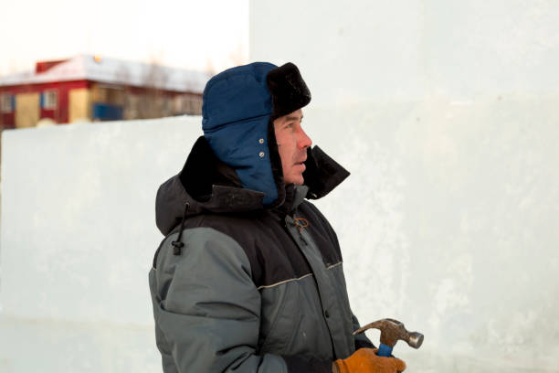 istock Worker in winter overalls with a hammer in his hand 1370404131